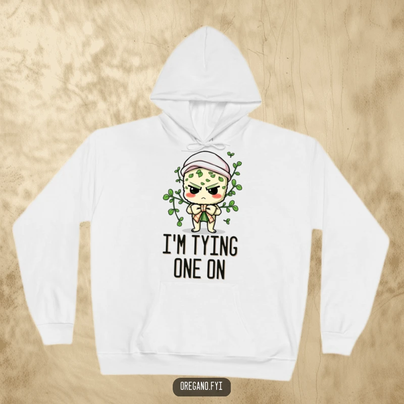 Funny hoodie showcasing a determined oregano character comically trying to tie a culinary bow, perfect for cozy, humorous wear.